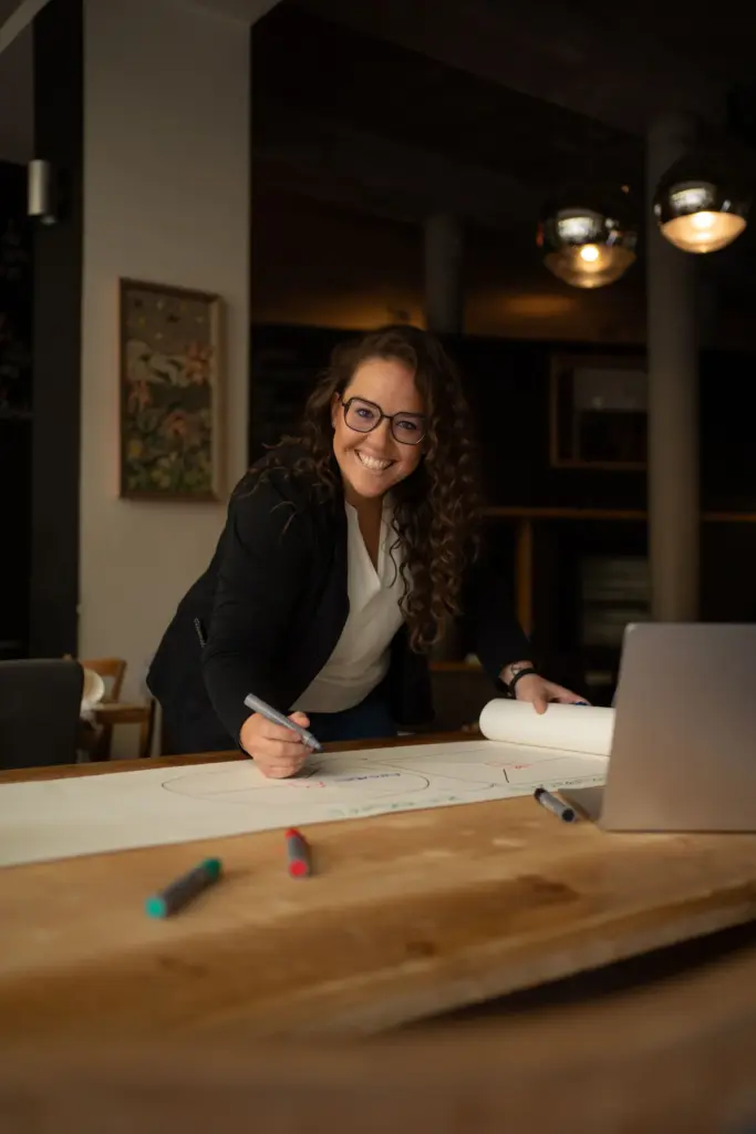 Lachende Frau bei der Arbeit an einem Konzept im modernen Büro – authentische Corporate Fotografie