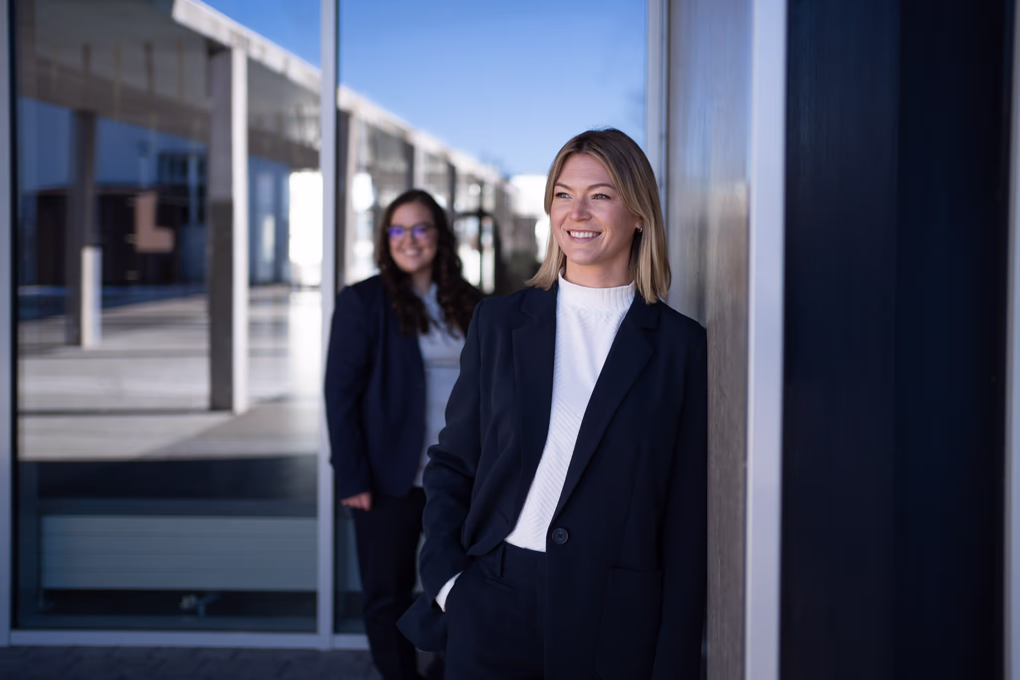 Zwei lächelnde Mitarbeiterinnen vor einem modernen Bürogebäude – Corporate Fotografie von Christian Meßner