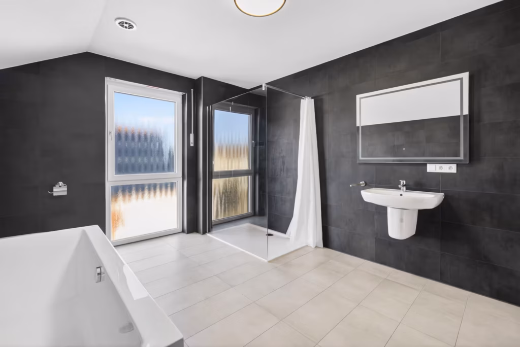 Modernes Badezimmer mit bodengleicher Dusche, Badewanne, dunklen Wandfliesen und Tageslicht