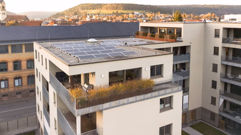 Drohnenaufnahme eines modernen Mehrfamilienhauses mit Solaranlage und großzügigen Balkonen