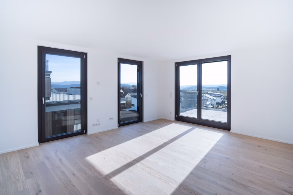 Heller, moderner Wohnraum mit großen Fensterfronten und freier Aussicht über die Dächer der Stadt