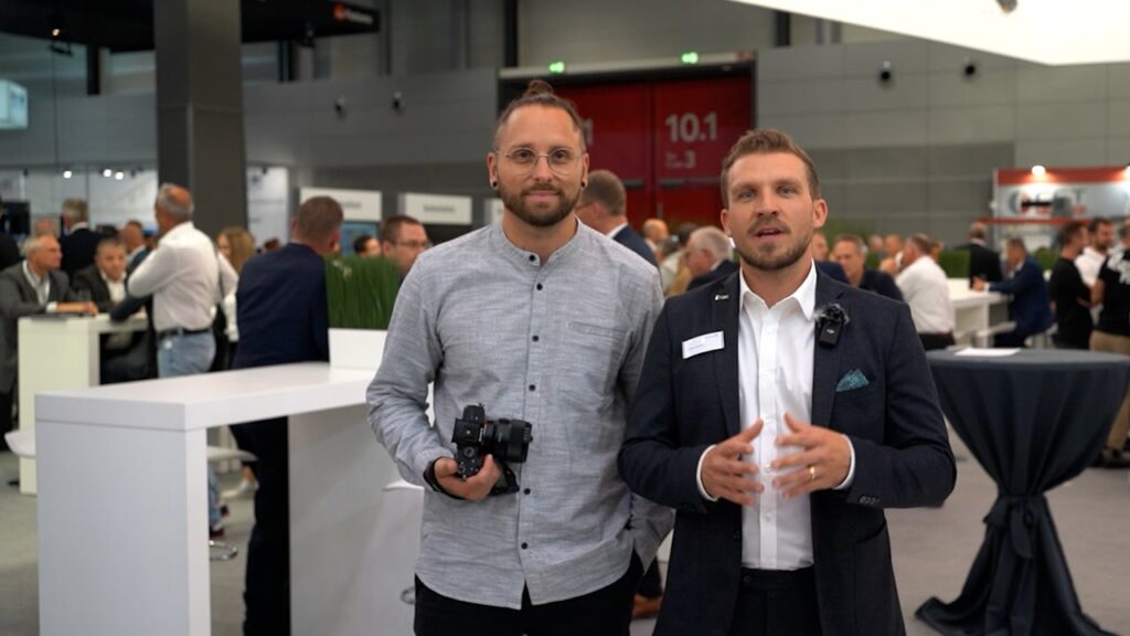 Fotograf und Mitarbeiter der Chiron Group auf der AMB Stuttgart, im Hintergrund der Messestand mit Besuchern